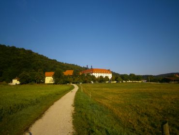 Schön gelegen an der Sonnenseite eines bewaldeten Tals liegt das alte Kloster, umgeben von ökologischen Viehweiden und Lindenbäumen. Die Barockanlage ist in einem Winkel von 120° gebaut, ähnlich wie die Bienenzelle.
