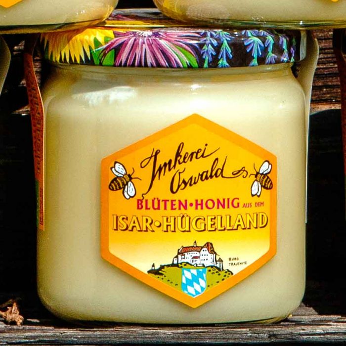 Ein Glas guten Honigs von Imkerei Oswald aus dem Isar-Hügelland. Das Glas ist im Freien vor dem Bienenhaus fotografiert.