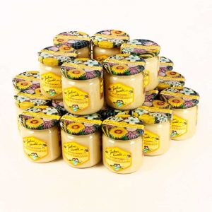 Ein Produktfoto, auf dem vierundzwanzig bunte Honiggläser mit bunten Blütendeckel in einer zweistöckigen Rundpyramide für dem Honigversand nett arrangiert sind.