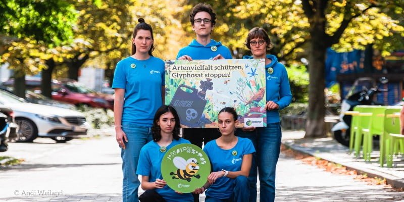 Junge Umweltaktivisten vom Umweltinstitut München halten Schilder mit der Aufschrift: Artenvielfalt schützen und Glyphosat stoppen.