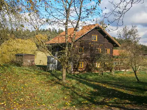 Ein Bauernhaus aus Holzblockbau im Rottal. Links daneben ein Bienenhaus.