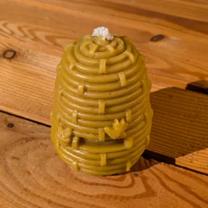 Dunkle Bienenwachskerze Bienenkorb von der Imkerei Oswald, handgefertigt aus natürlichem Bienenwachs mit kleinen Bienen-Verzierungen, auf einem rustikalen Holztisch.