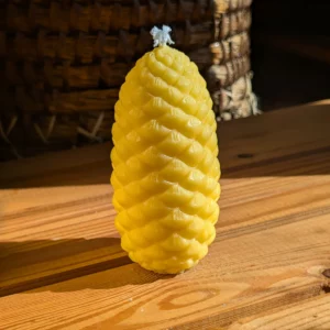 Bienenwachskerze in Form eines Pinienzapfens von Imkerei Oswald auf einem Holztisch