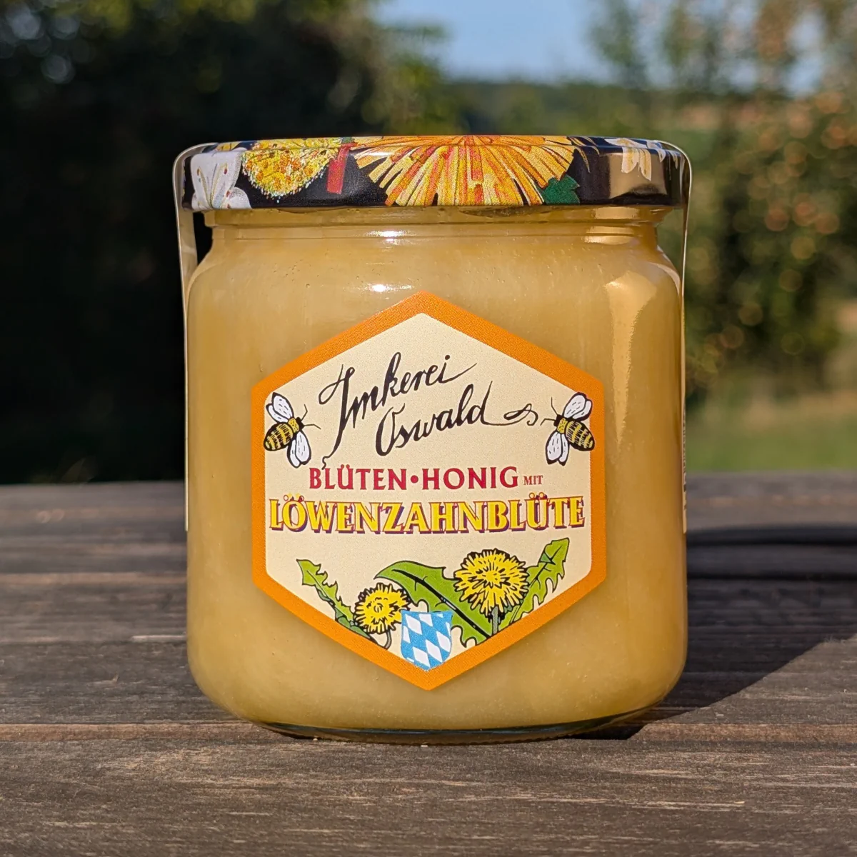 Bio Blütenhonig mit Löwenzahn von Imkerei Oswald im Glas vor sonniger Naturkulisse