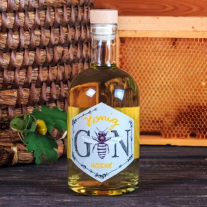Eine Apothekerflasche mit Honig Gin 40% vol. Auf dem Etikett ist eine Honigbiene als Buchstabe "i", und handgezeichnete Randverzierung mit stilisierten Wacholderbeeren zu sehen. Dieser gute Gin ist erhältlich im Online Versand Shop von Imkerei Oswald bio-honig com.