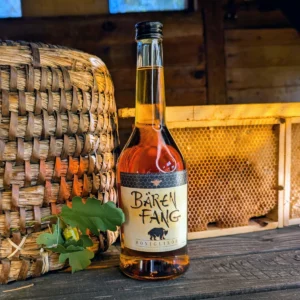 Zu den Hof Spezialitäten wie Honigwein und Likör zählt beispielhaft der ostpreussische Bärenfang, der hier im Bienenhaus vor einer Honigwabe und einem Bienenkorb steht.