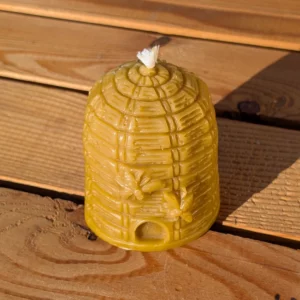 Handgefertigte, dunkel-goldene Kerze Bienenkorb von Imkerei Oswald, hergestellt aus echtem Bienenwachs. Diese detailreiche Kerze in Bienenkorbform mit sichtbarem Docht, zwei kleinen Bienen und einem Eingang steht auf einem rustikalen Holztisch und ist ideal für eine natürliche Dekoration. Ein perfektes Produkt für Liebhaber von Kerzen Bienenkorb.