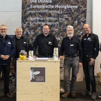 Messestand des Bundesverbands Dunkle Biene Deutschland e.V. mit Vertretern vor dem Informationsbanner zur Dunklen Biene (Apis mellifera mellifera), der ursprünglichen Urbiene Deutschlands.